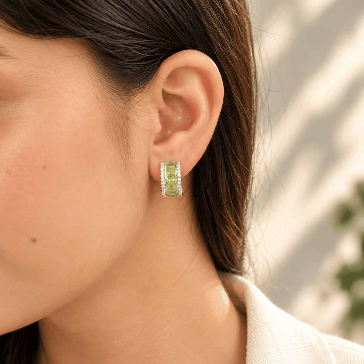 Model wearing 925 sterling silver peridot channel set half hoop earrings