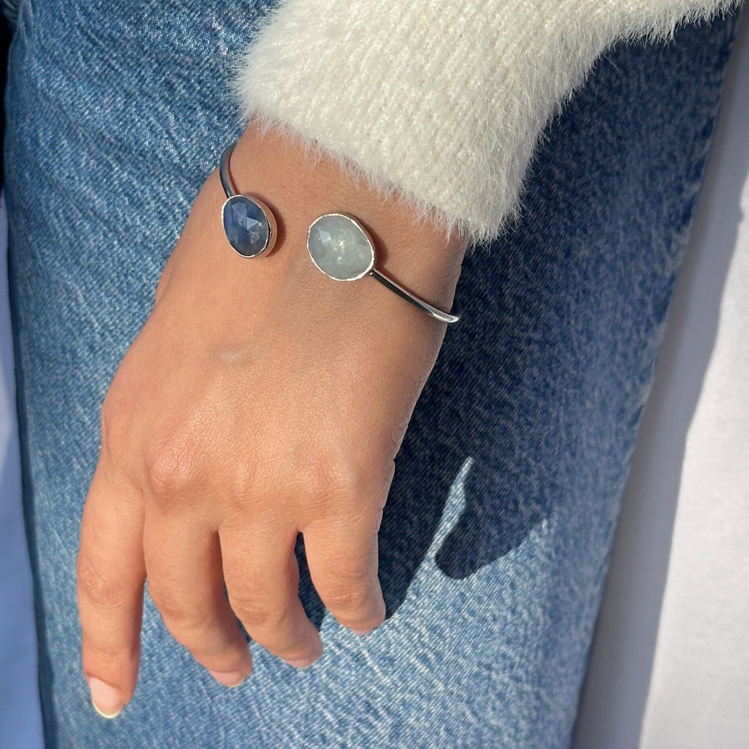 Hand wearing a silver bracelet with circular charms against a denim background

sapphire bracelet,  silver bracelet 