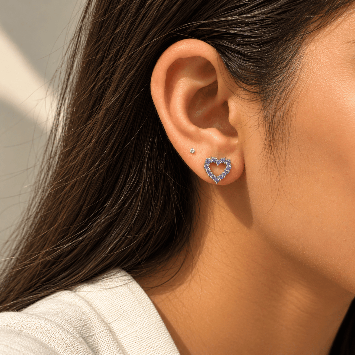 Model wearing 925 sterling silver tanzanite open heart stud earrings