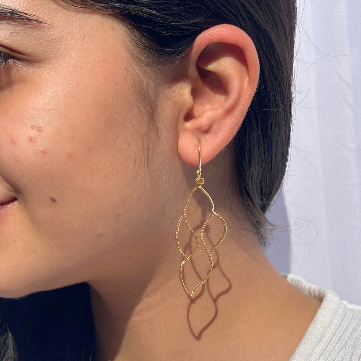 Earrings, Golden earrings, Close-up of a person wearing gold earrings with a neutral background