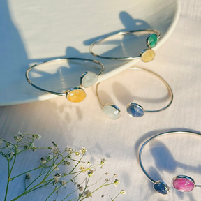Set of silver bangles with colorful stones on a light surface with flowers.

sapphire bracelets, silver bracelets 