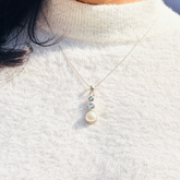 Pearl necklace with blue gemstones on a white sweater