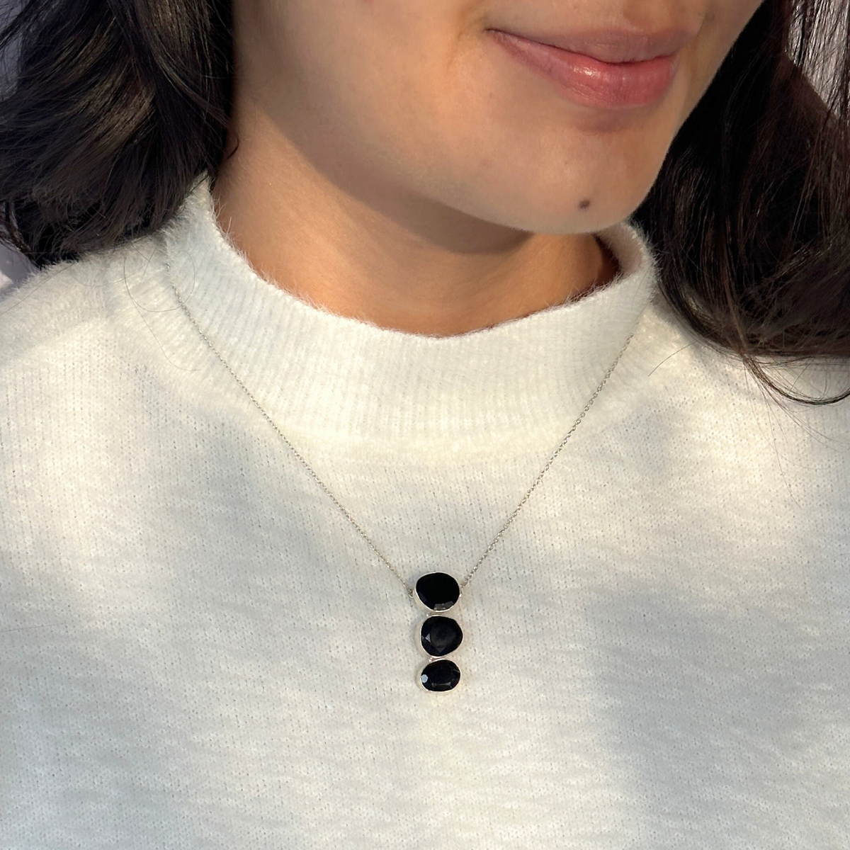 Natural black onyx gemstone silver necklace

Black onyx 925 sterling silver pendant

Black onyx stone silver necklace India

Elegant black onyx silver necklace online

Minimal pendant 

Minimal necklace for daily wear 


Person wearing a white sweater with a necklace featuring three black stones.