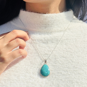 Turquoise pendant necklace on a white sweater