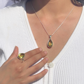 Lemon quartz silver 925 pendant for women

Natural lemon quartz gemstone silver pendant

Soft yellow lemon quartz 925 silver pendant

Lemon quartz stone silver pendant 

Elegant lemon quartz silver pendant online

Minimal green pendant

minimal pendant 

Pendant for daily wear


Teardrop-shaped pendant and ring with green gemstones worn by a person in a white outfit.